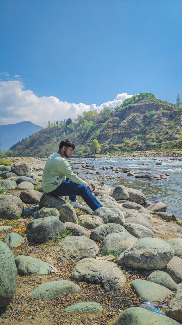 Sitting on the boulders of a river bed in a green valley